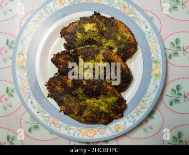 Maison de trois tranches de Kingfish frits à la perfection dans une pâte verte faite de feuilles de Corriander, herbes et épices. Banque D'Images