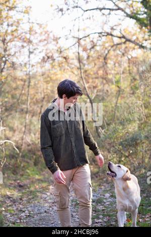 Jeune homme avec chien marchant dans la forêt d'automne le week-end Banque D'Images