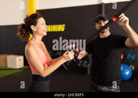Instructeur de fitness souriant assistant sportswoman dans la salle de gym Banque D'Images