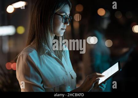 Femme d'affaires travaillant sur une tablette numérique au bureau tard dans la nuit Banque D'Images