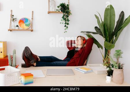 Femme d'affaires sans souci avec un casque se détendant dans un bureau créatif Banque D'Images