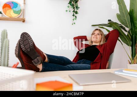Femme d'affaires attentive, tête derrière la tête, se détendant dans un bureau créatif Banque D'Images