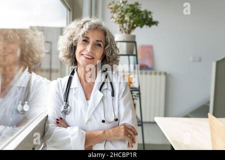 Médecin senior attentif, qui regarde par la fenêtre à la maison Banque D'Images