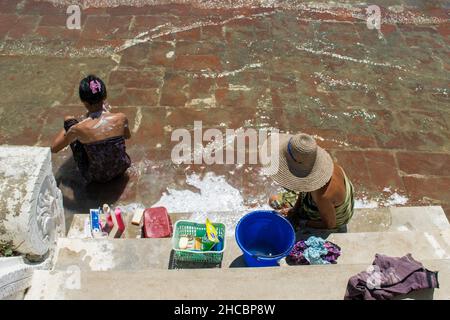 Les gens se baignent et se lavent sur la rive de la rivière Irrawaddy, à côté des statues de chinthe, en Birmanie Banque D'Images