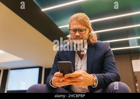 Homme d'affaires avec lunettes utilisant le téléphone portable à la station de métro Banque D'Images