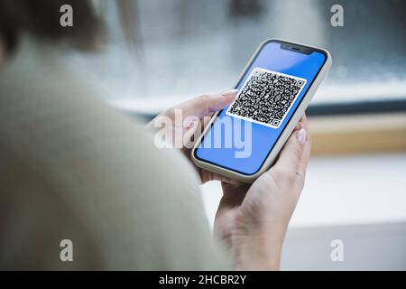 Femme tenant un téléphone portable avec un code QR à l'écran Banque D'Images
