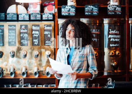 Femme d'affaires réfléchie avec document en magasin Banque D'Images