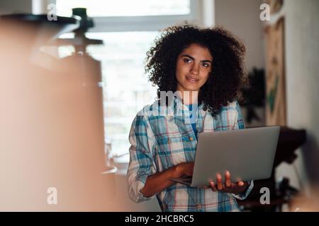 Femme d'affaires attentionnée avec un ordinateur portable dans la maîtrise du café Banque D'Images