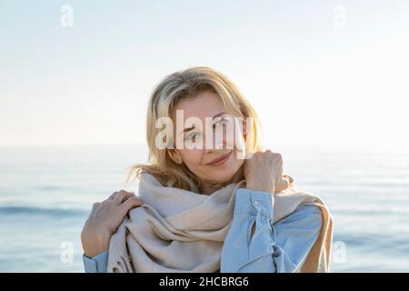 Femme contemplative portant un foulard à la plage Banque D'Images