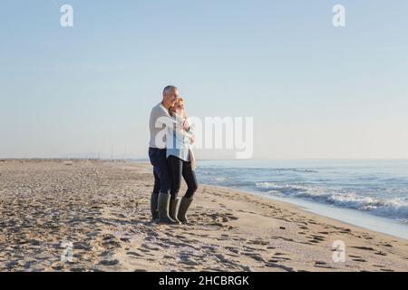 Couple embrassant l'un l'autre debout sur le sable à la plage Banque D'Images