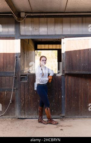 Femme souriante s'appuyant sur un cheval stable Banque D'Images