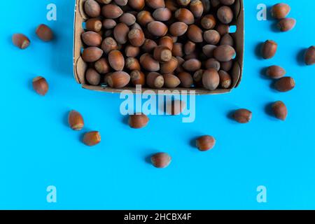 Boîte de noisettes sur table en pierre, platines sur fond bleu Banque D'Images