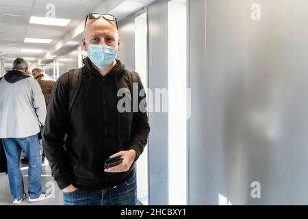 Un touriste portant un masque de protection et un sac à dos attendant à bord de l'aéroport Banque D'Images