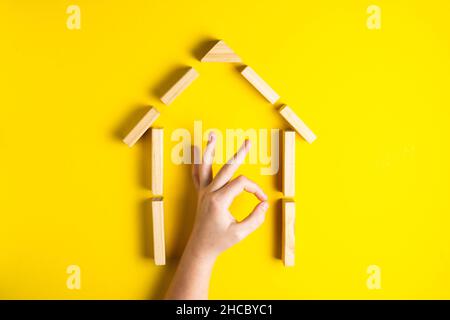Vue de dessus de la main de l'enfant gros plan des blocs de construction montrant ok, maison, cabane en bois Banque D'Images