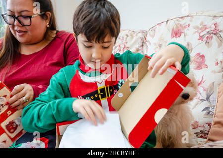 Mère et son fils se sont assis ensemble sur un cadeau d'ouverture de seettee le jour de Noël Banque D'Images