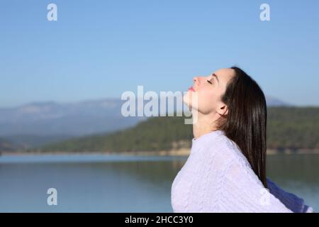 Vue latérale portrait d'une femme détendue respirant de l'air frais dans un lac de montagne Banque D'Images