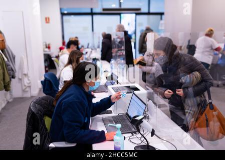 Une femme s'entretient avec une infirmière alors qu'elle est reçue dans un centre de vaccination à Barcelone, Espagne, le 22 décembre 2021.Suite à la propagation de l'Omicron Banque D'Images