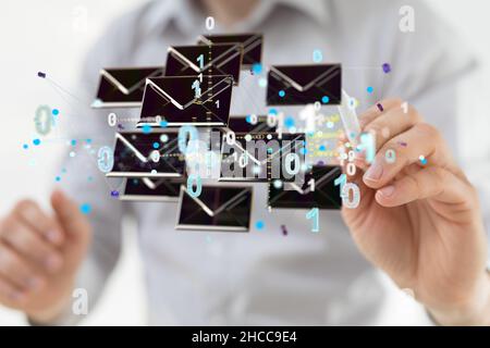 Gros plan de la main avec un stylo pointant vers les icônes flottantes d'e-mail et les nombres binaires. Banque D'Images