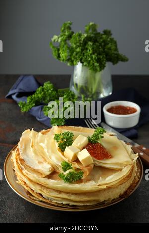 Crêpes. Concept de nourriture savoureuse avec des crêpes et des herbes sur une table sombre texturée, verticale. Crêpes Banque D'Images