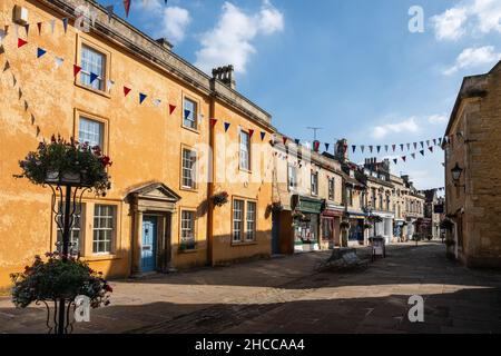Les boutiques et les bureaux sont décorés de banderoles et de paniers de fleurs sur la traditionnelle High Street de Corsham dans le Wiltshire. Banque D'Images