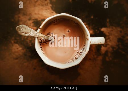 Vue de dessus d'une belle tasse grise avec chocolat chaud délicieux avec lait et une cuillère à café d'argent.Une bonne boisson pour le petit déjeuner.Photos de nourriture. Banque D'Images