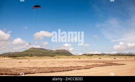 Les gens volent des kits sur la plage de Black Rock Sands près de Porthmadog, avec les montagnes de Snowdonia derrière. Banque D'Images