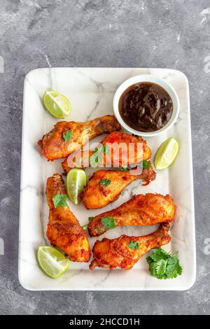 Pilons de poulet cuits sur un plateau blanc avec condiment Top Down photo Banque D'Images