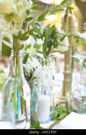 Plan vertical de fleurs décoratives dans des vases en verre sur une nappe blanche prête pour un événement Banque D'Images