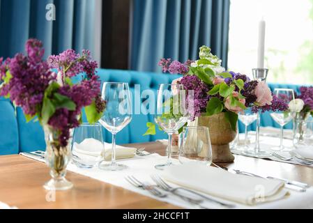 Photo sélective de fleurs lilas dans des vases et autres cadres sur une table en bois dans un café Banque D'Images