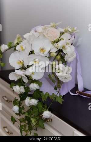 Plan vertical d'un bouquet de freesia avec des feuilles vertes sur une commode en bois Banque D'Images