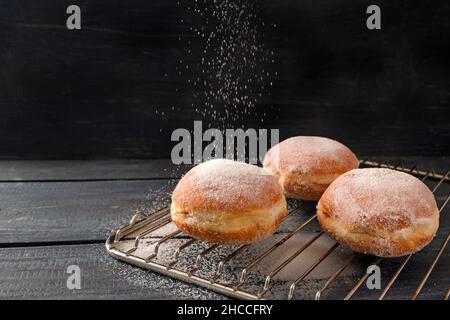 Sur une grille de cuisson, les beignets de Krapfen ou de Berliner sont saupoudés de sucre, de pâte frite pour le nouvel an ou le carnaval, de fond rustique foncé en bois, Copy sp Banque D'Images