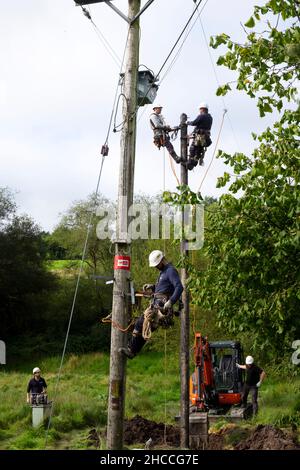 Travailleurs de l'électricité remplaçant l'ancien poteau de service public et rebranchant les câbles d'équipement électrique sur la propriété rurale au pays de Galles Grande-Bretagne KATHY DEWITT Banque D'Images