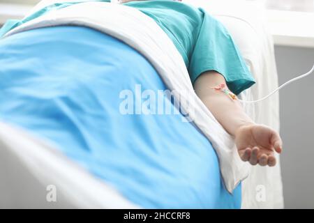 Patient mâle allongé sur le lit avec perfusion intraveineuse dans sa main rapprochée Banque D'Images