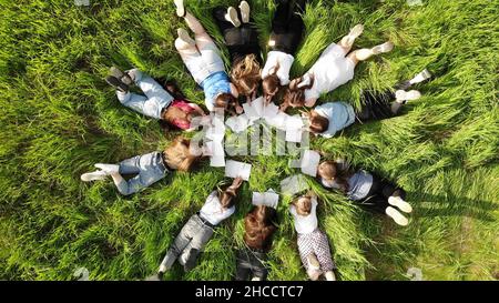 Les jeunes filles s'étendent sur l'herbe dans un parc de la ville avec des carnets. Banque D'Images