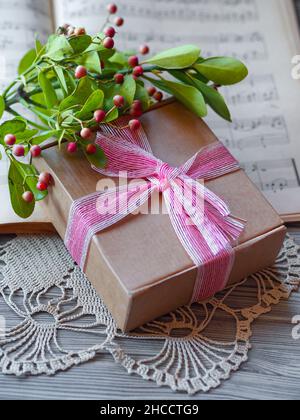 Cadeau de noël avec noeud rose, notes musicales et branche de Christmasberry Banque D'Images
