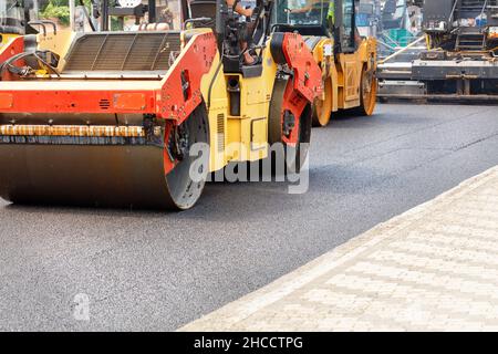 Construction d'une nouvelle route, rouleaux compactant de l'asphalte frais sur la route immédiatement après les finisseurs un jour d'été. Banque D'Images