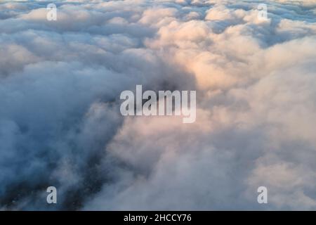 Vue aérienne depuis la haute altitude de la ville éloignée couverte de cumulus bouffieux qui se forment avant la pluie en soirée.Point de vue de l'avion du ciel nuageux Banque D'Images