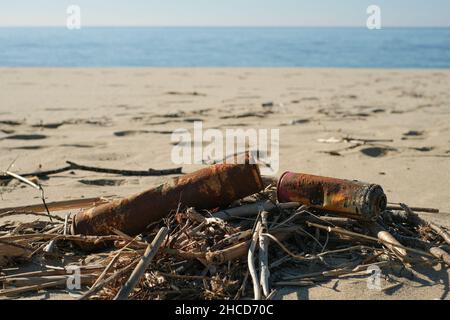 Vieux bombes de pulvérisation rouillées jetées sur l'écosystème de la côte de mer, pollution de la nature contamination Banque D'Images