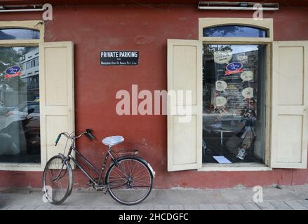 Vélo penchée sur un bâtiment rouge clos à Bangalore, Inde. Banque D'Images