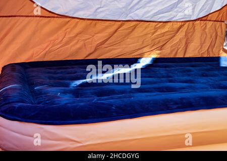 Mise au point sélective d'un matelas pneumatique gonflable sur le sol d'une tente en cours de remplissage. Banque D'Images