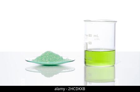 Sulfate ferreux dans le verre de surveillance chimique placer à côté du liquide sulfate de fer (II) dans le bécher.Gros plan sur l'ingrédient chimique sur la table de laboratoire blanche.Côté Banque D'Images