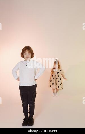 Jolis petits enfants tendance sur un fond.Jolie petite fille et garçon en costume décontracté sur le fond.Concept de mode pour enfants Banque D'Images