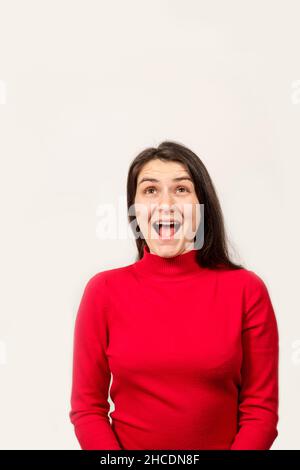 Une femme brune dans un chandail rouge rit avec sa bouche ouverte et regarde vers le haut, un endroit pour le texte Banque D'Images