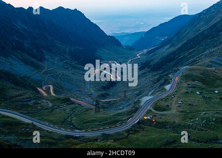 La route courbe de Transfagarasan vue avec des feux de route de voiture à l'heure bleue. Photo prise le 31 août 2019, comté de Sibiu, Roumanie. Banque D'Images