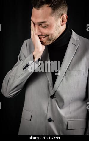 portrait d'un jeune homme d'affaires dans un costume gris qui est extrêmement fatigué frotte son visage essayant de récupérer Banque D'Images