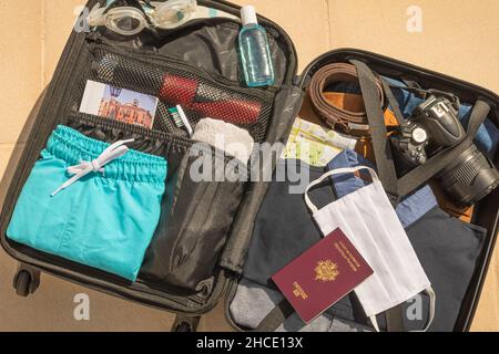 Valise à roulettes avec masque de protection du visage et gel hydroalcoolique pour lutter contre le virus Covid-19, le coronavirus, l'allergie, l'épidémie et la pandémie. Banque D'Images