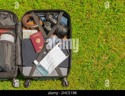 Valise à roulettes avec masque de protection du visage et gel hydroalcoolique pour lutter contre le virus Covid-19, le coronavirus, l'allergie, l'épidémie et la pandémie. Banque D'Images