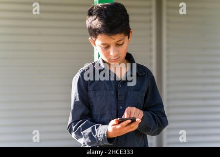 Préadolescents de jeunes garçons utilisant un téléphone portable.Enfant tapotant sur l'écran du téléphone cellulaire. Banque D'Images