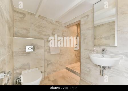 Intérieur moderne de la salle de bains avec douche et wc en céramique sur sol carrelé beige dans l'appartement dans le style minimaliste Banque D'Images