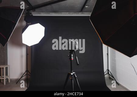 Intérieur de studio photo moderne avec octaboxes et appareil photo professionnel sur trépied sur fond noir Banque D'Images